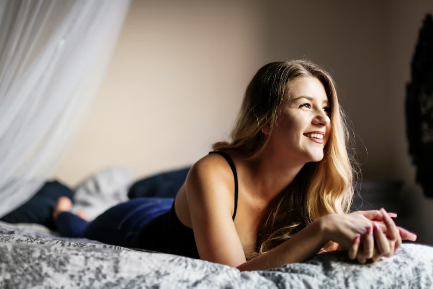 A smiling young woman lying on a bed